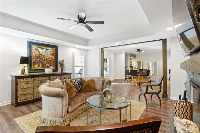 living room featuring a raised ceiling, dark hardwood / wood-style floors, and ceiling fan