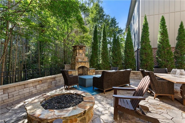 view of patio with a fire pit and an outdoor stone fireplace