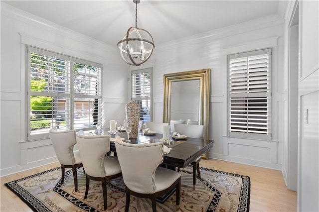 dining room with a healthy amount of sunlight, ornamental molding, a chandelier, and light hardwood / wood-style flooring