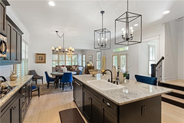 kitchen featuring sink, dark brown cabinets, a center island with sink, appliances with stainless steel finishes, and pendant lighting