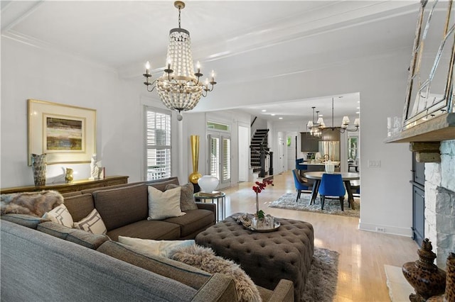 living room featuring an inviting chandelier, a stone fireplace, light hardwood / wood-style flooring, and crown molding