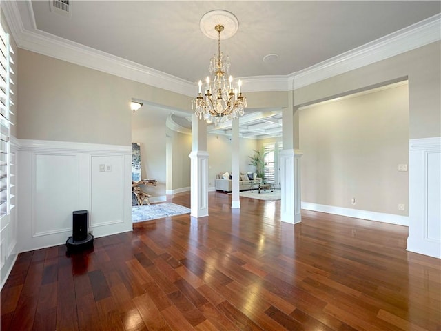 unfurnished dining area with a notable chandelier, decorative columns, wood finished floors, visible vents, and ornamental molding