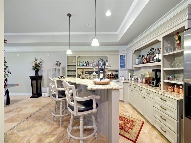 kitchen featuring crown molding, open shelves, light stone countertops, a breakfast bar, and a raised ceiling