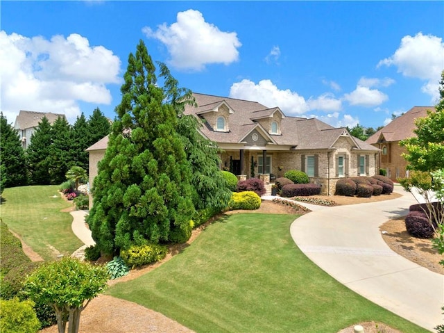 cape cod home with stone siding and a front yard