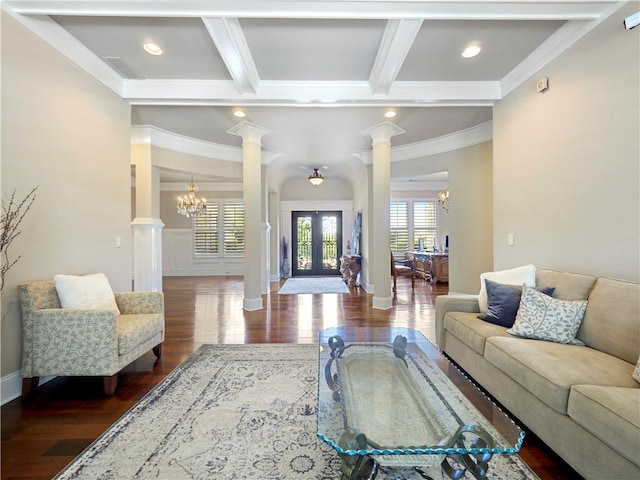 living room with decorative columns, crown molding, beam ceiling, wood finished floors, and a notable chandelier