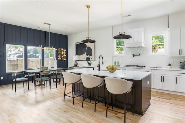 kitchen featuring light countertops, backsplash, a sink, light wood-type flooring, and white cabinetry