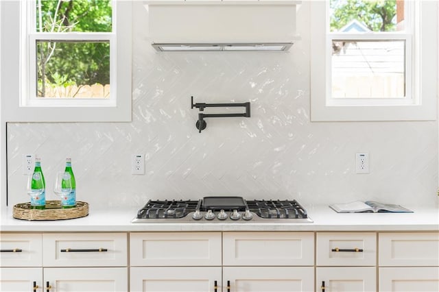 kitchen with light countertops, decorative backsplash, white cabinets, and stainless steel gas cooktop