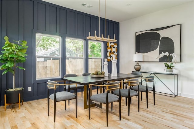 dining area with a decorative wall, light wood-type flooring, and a wealth of natural light