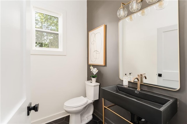 half bath featuring tile patterned flooring, vanity, toilet, and baseboards
