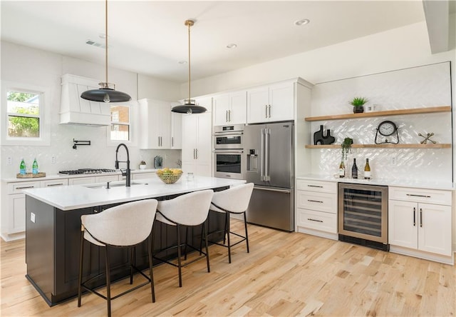 kitchen with wine cooler, backsplash, light countertops, appliances with stainless steel finishes, and white cabinetry
