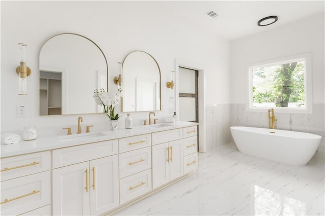 full bathroom with double vanity, visible vents, a wainscoted wall, and a sink