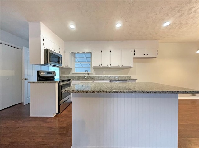 kitchen with white cabinetry, dark hardwood / wood-style flooring, a center island, and appliances with stainless steel finishes