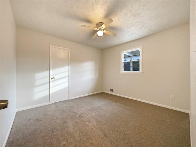 carpeted spare room featuring ceiling fan and a textured ceiling