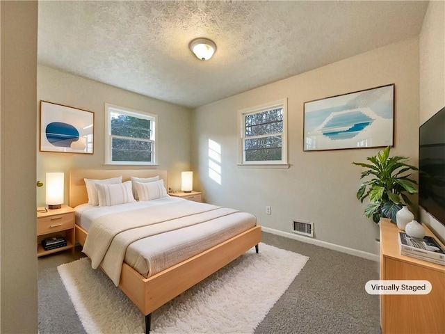 bedroom featuring dark carpet and a textured ceiling