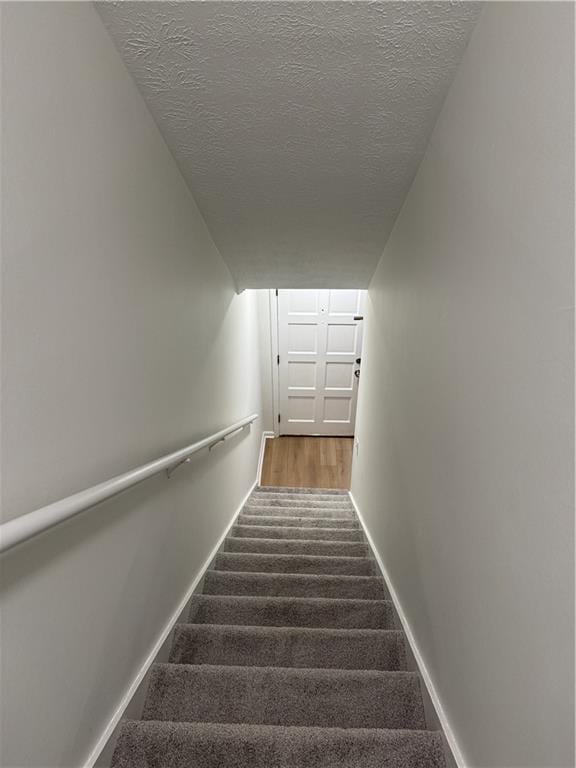 stairs with a textured ceiling and carpet floors