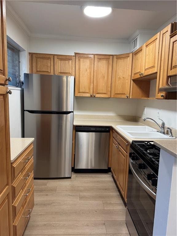 kitchen with ornamental molding, sink, stainless steel appliances, and light wood-type flooring