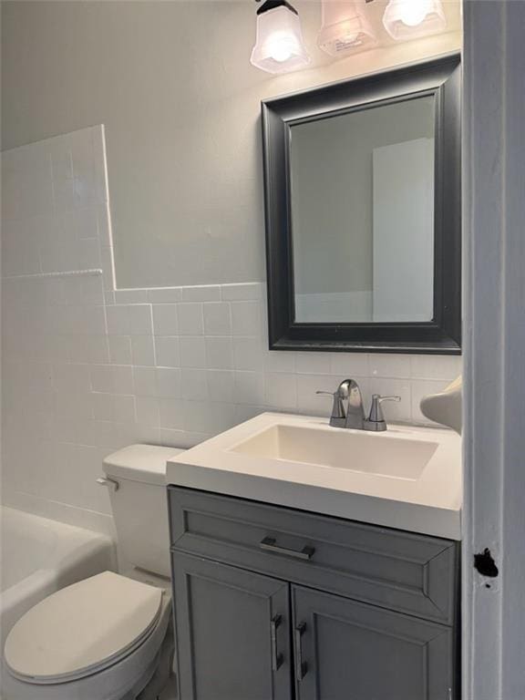 bathroom featuring tasteful backsplash, vanity, tile walls, and toilet