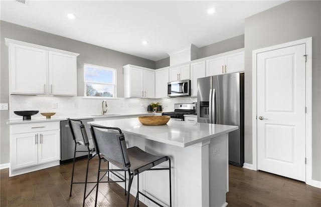 kitchen featuring white cabinets, a center island, appliances with stainless steel finishes, and a sink