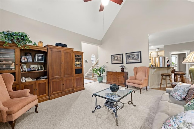 carpeted living room with ceiling fan and high vaulted ceiling