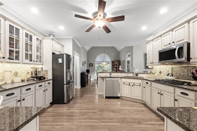 kitchen featuring dark stone countertops, sink, lofted ceiling, and appliances with stainless steel finishes