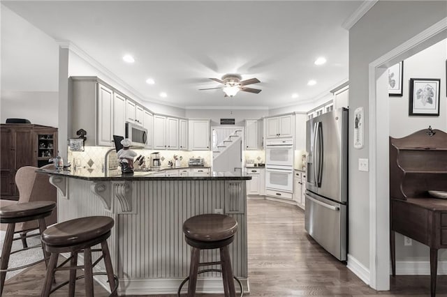 kitchen featuring a breakfast bar area, kitchen peninsula, decorative backsplash, and stainless steel appliances