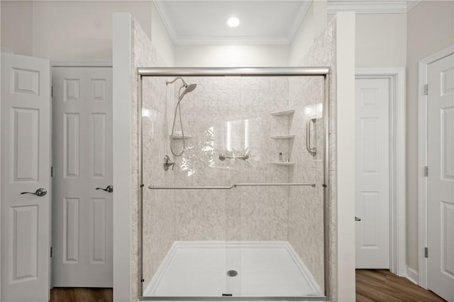 bathroom with a shower with door, hardwood / wood-style floors, and ornamental molding