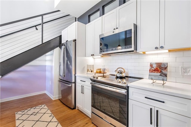 kitchen featuring light wood finished floors, appliances with stainless steel finishes, decorative backsplash, and light countertops