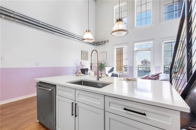 kitchen with a sink, light countertops, stainless steel dishwasher, and open floor plan