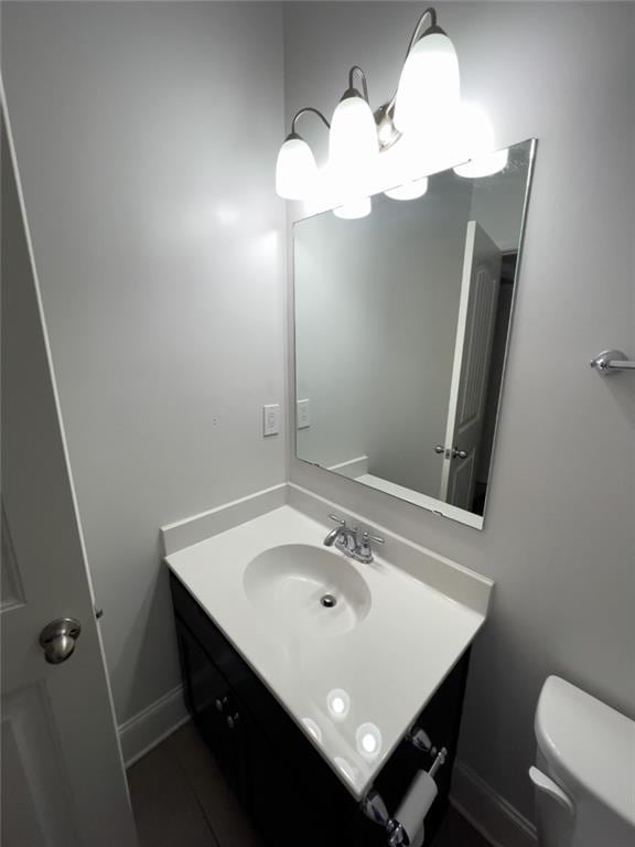 bathroom featuring baseboards, toilet, and vanity