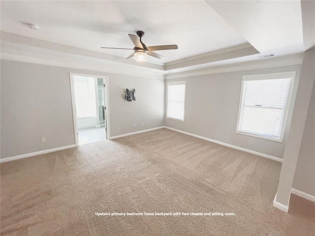 carpeted spare room with a raised ceiling, ornamental molding, baseboards, and ceiling fan