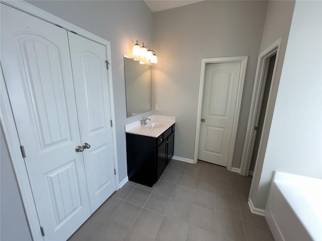 bathroom with tile patterned flooring, a tub, vanity, and baseboards