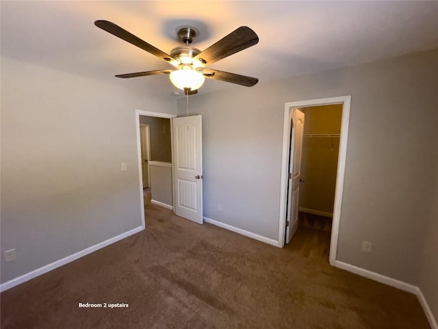 unfurnished bedroom featuring a closet, carpet floors, baseboards, ceiling fan, and a spacious closet