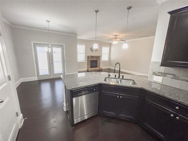 kitchen featuring light stone countertops, a sink, a stone fireplace, dishwasher, and open floor plan