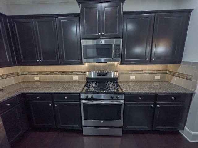 kitchen featuring stone counters, backsplash, appliances with stainless steel finishes, and dark cabinetry