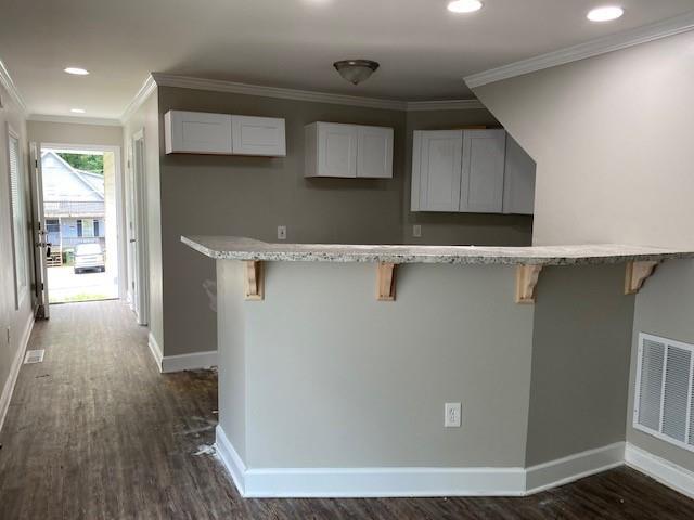 kitchen with white cabinets, ornamental molding, and a breakfast bar area