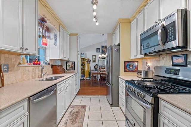 kitchen with lofted ceiling, backsplash, sink, light tile patterned floors, and stainless steel appliances