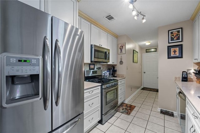 kitchen with tasteful backsplash, white cabinetry, light tile patterned flooring, and stainless steel appliances