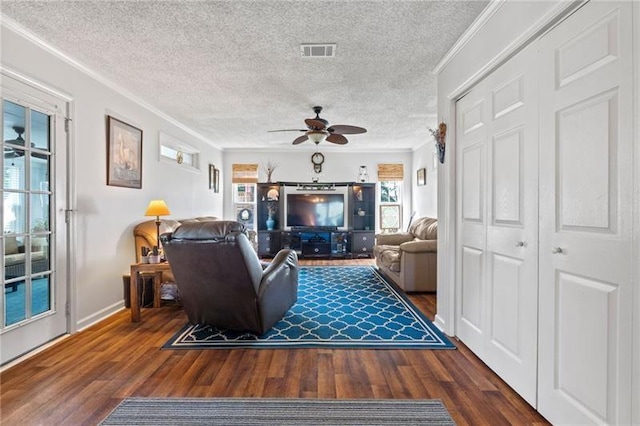 living room featuring ceiling fan, dark hardwood / wood-style floors, ornamental molding, and a textured ceiling