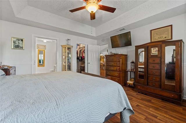 bedroom with ceiling fan, a closet, a walk in closet, and a tray ceiling