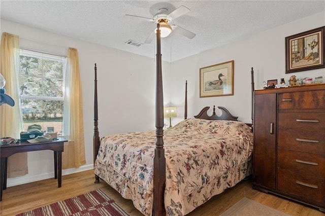 bedroom featuring ceiling fan, wood-type flooring, and a textured ceiling