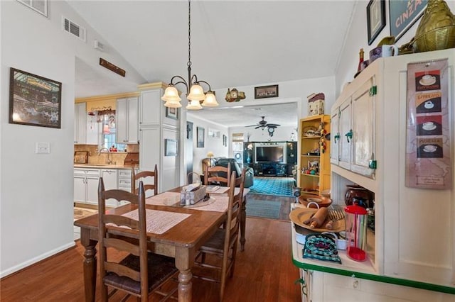 dining space featuring ceiling fan with notable chandelier, dark hardwood / wood-style floors, lofted ceiling, and sink