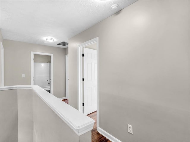 hall featuring a textured ceiling and dark wood-type flooring