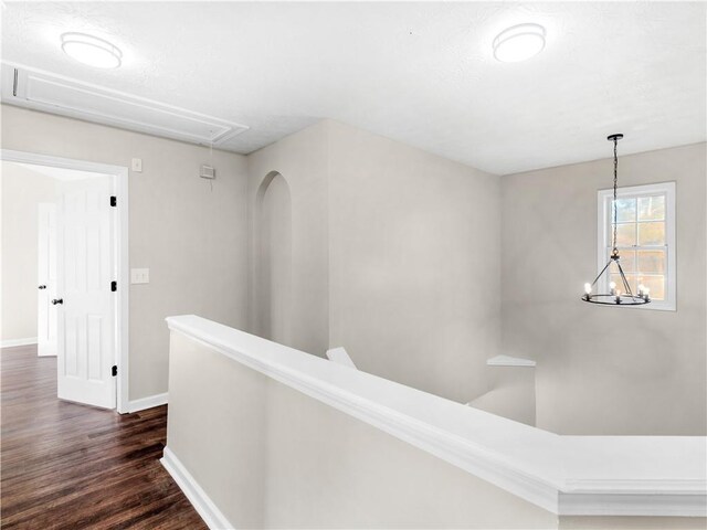 hall with dark hardwood / wood-style floors and an inviting chandelier