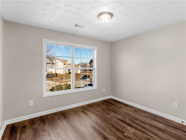 spare room with a textured ceiling and dark wood-type flooring