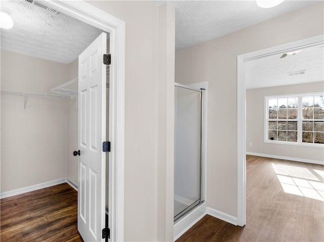 bathroom with a textured ceiling, wood-type flooring, and a shower with shower door