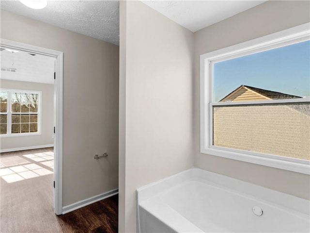 bathroom with hardwood / wood-style flooring, a bath, and a textured ceiling