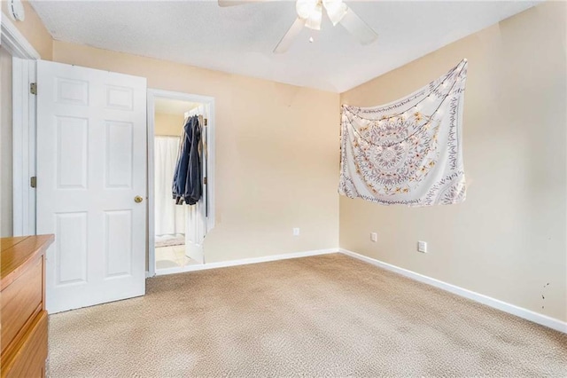 unfurnished bedroom with a closet, carpet, baseboards, ceiling fan, and a spacious closet