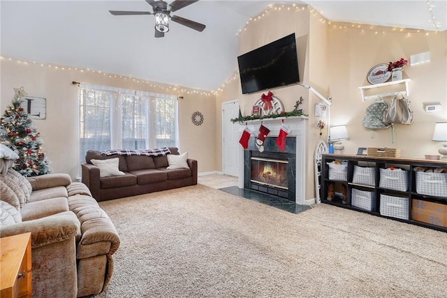 carpeted living room featuring baseboards, a fireplace with flush hearth, high vaulted ceiling, and a ceiling fan