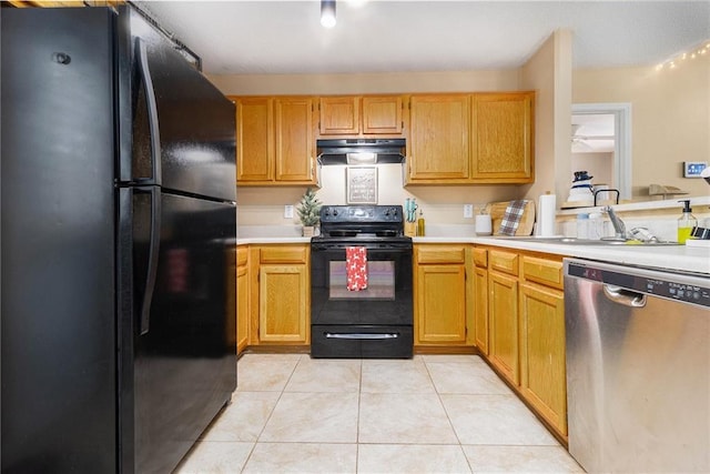 kitchen featuring light countertops, light tile patterned flooring, a sink, under cabinet range hood, and black appliances