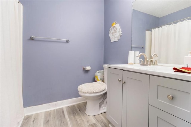 full bathroom with toilet, a shower with shower curtain, wood finished floors, vanity, and baseboards